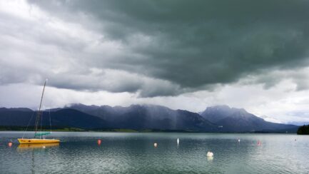 Segelboot auf dem Forggensee vor stürmischem Himmel