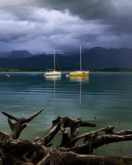 Segelboote auf dem Forggensee mit treibendem Holz und stürmischem Himmel